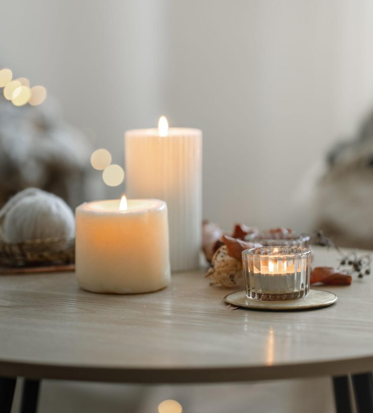 Cozy home composition with candles on blurred bokeh background. Beautiful burning candles in the interior of a room in a Scandinavian style.